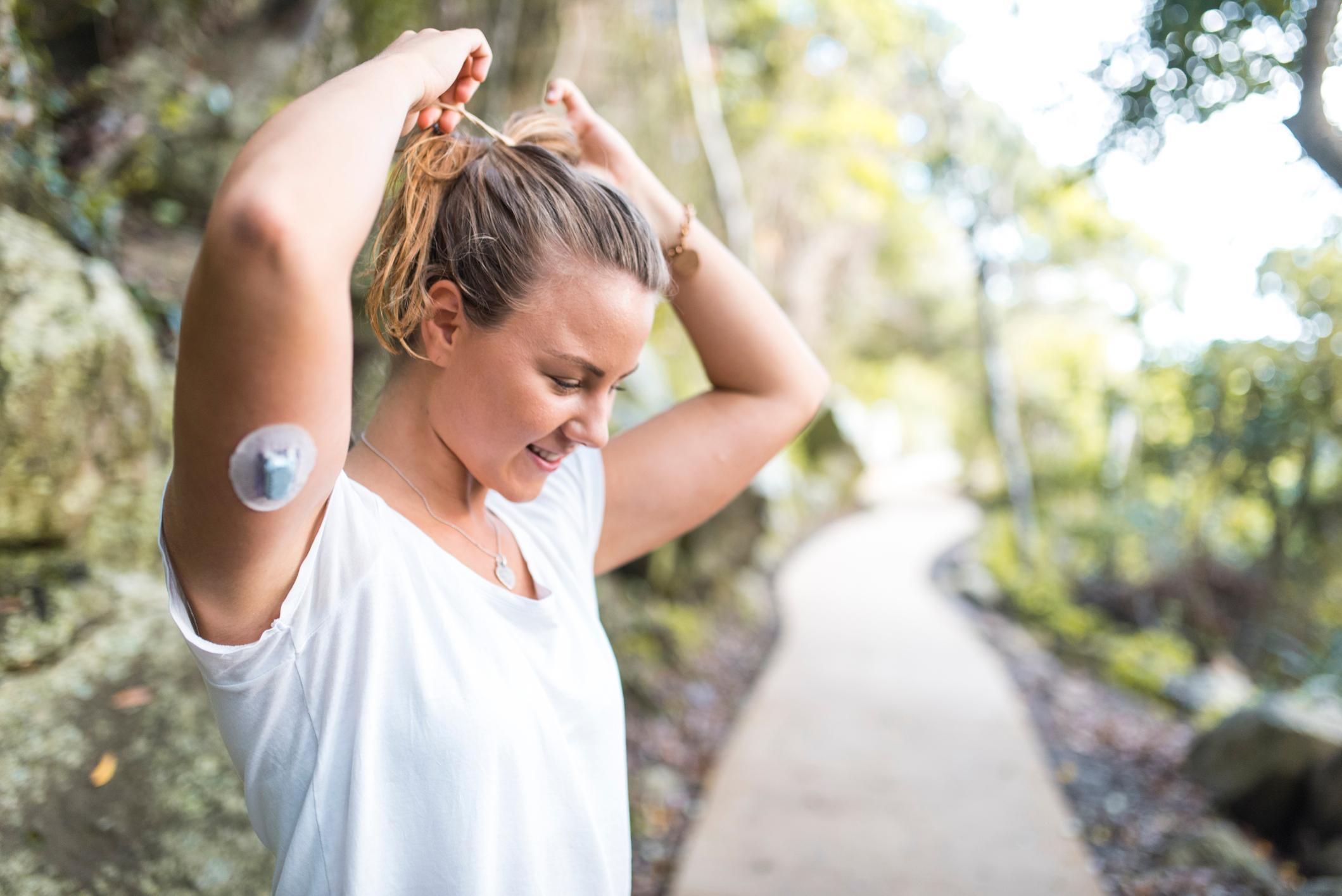 Woman exercising with continuous glucose monitor on arm