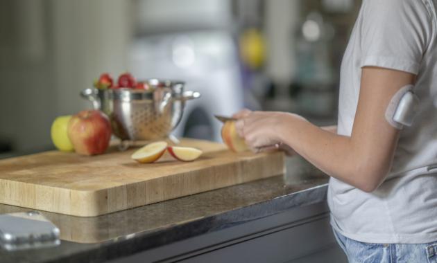 Person slicing apples wearing an Omnipod insulin pump patch