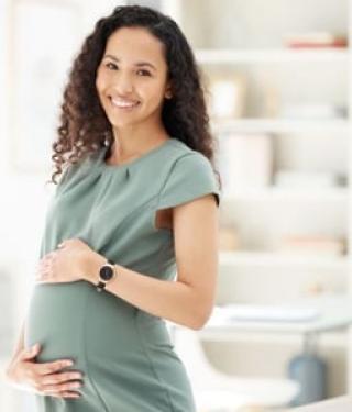 Pregnant woman smiling with hand on belly