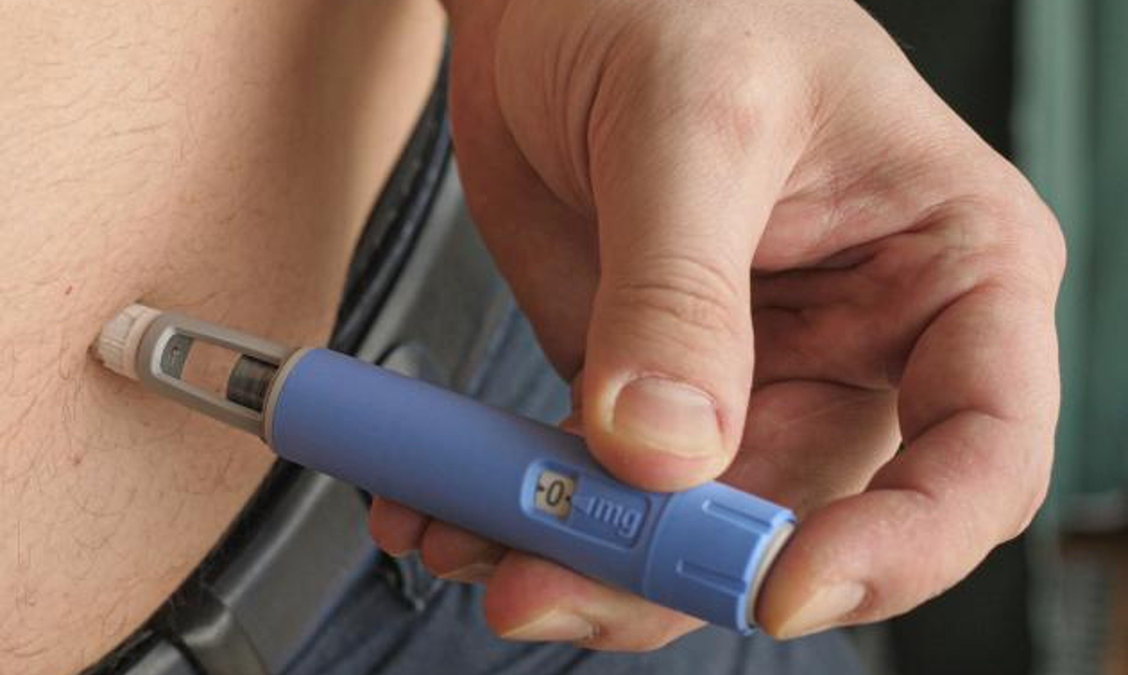 Man inserting Ozempic into stomach