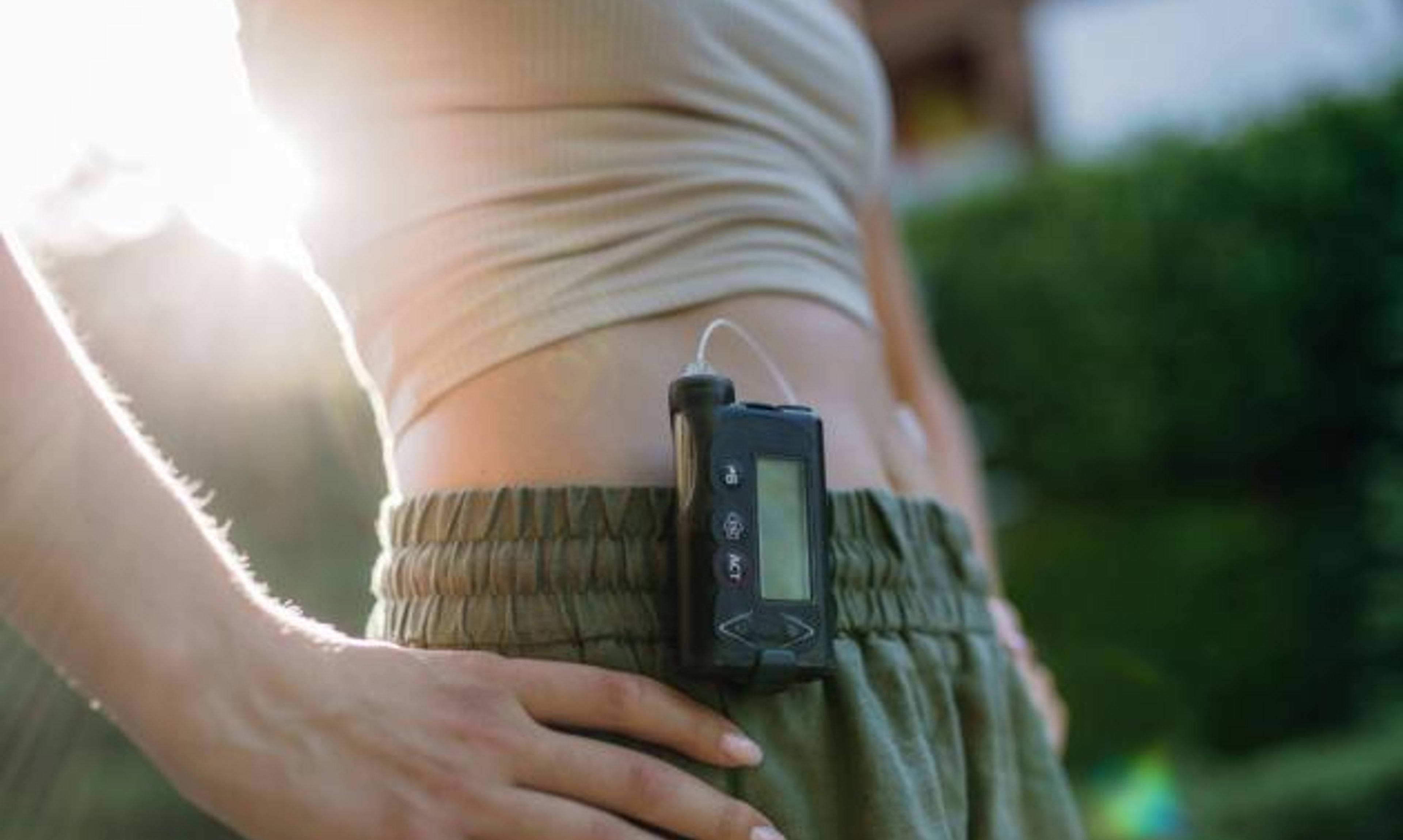 Woman wearing insulin pump with sun rising behind her.