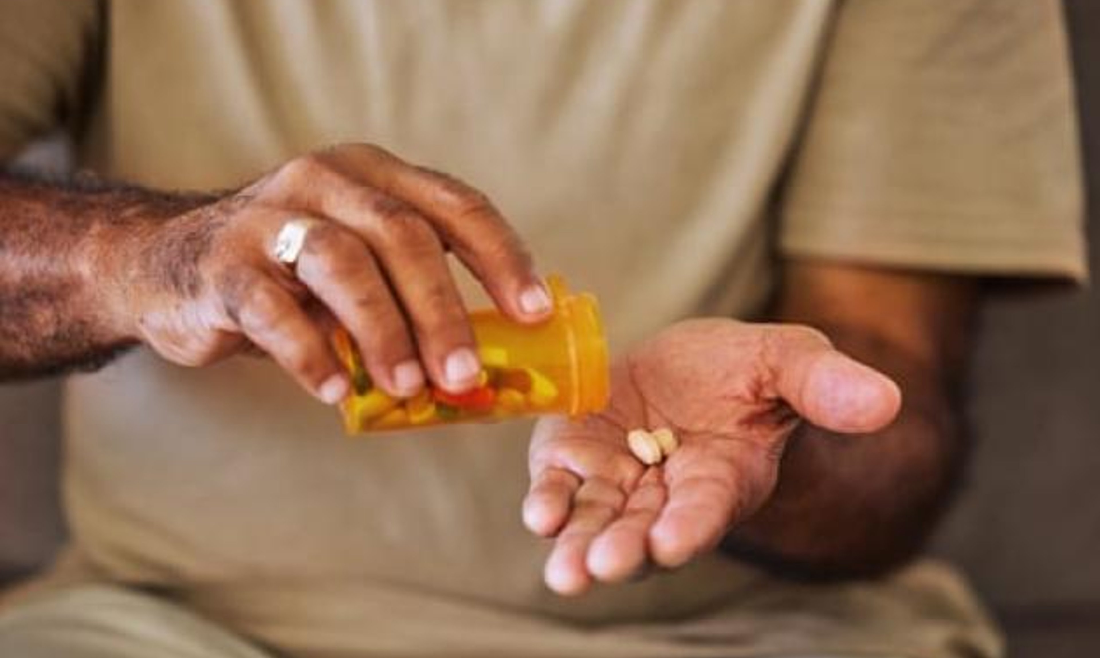 Man pours pills into his hand. 
