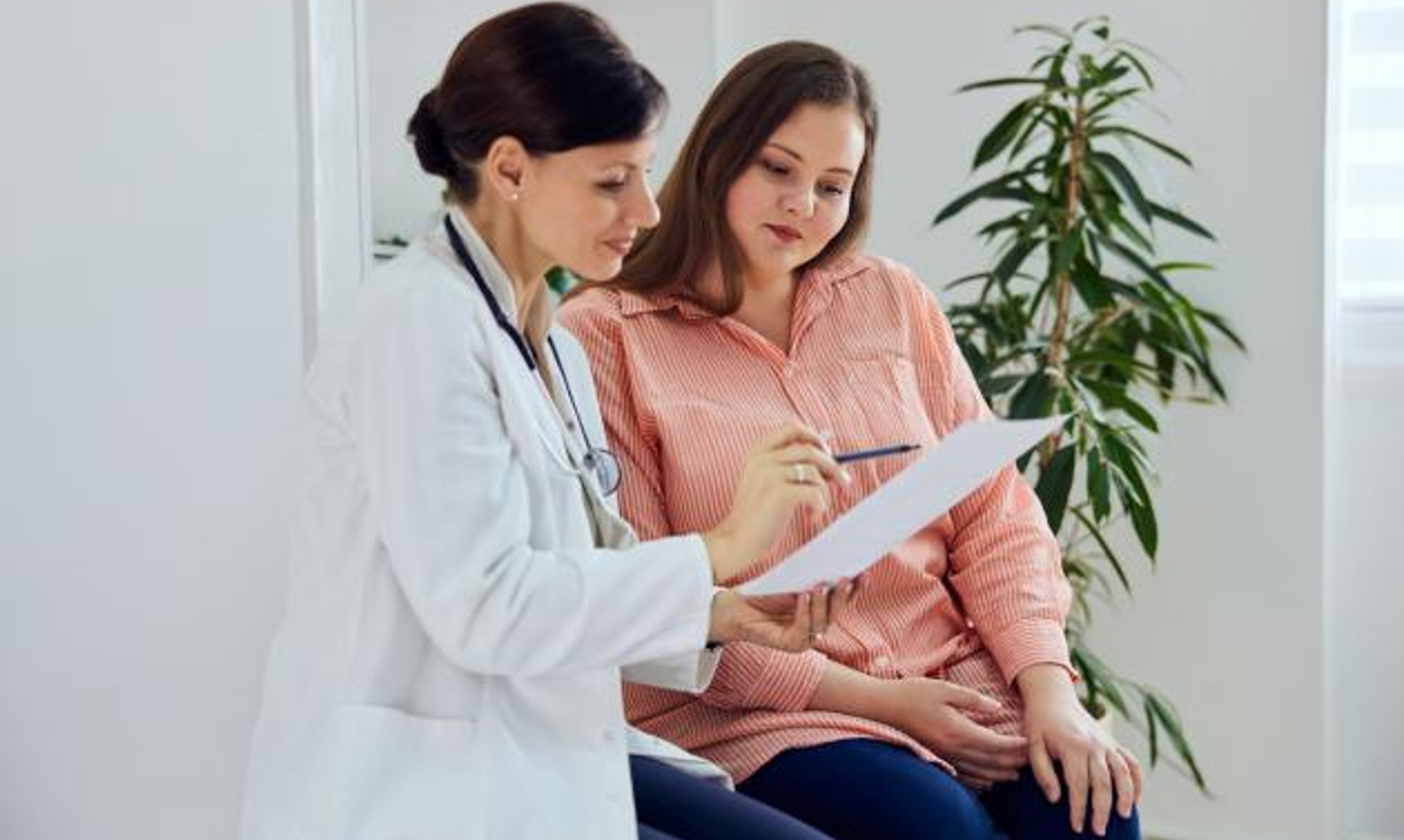 Woman reviewing paperwork with doctor and smiling
