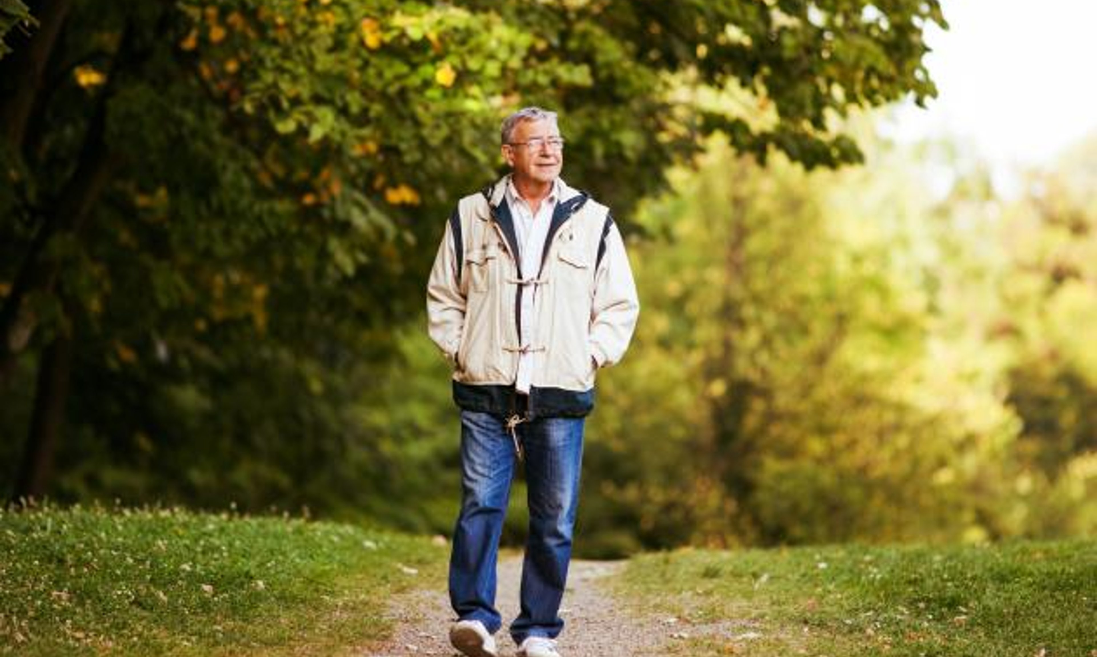 A man takes a walk on a path along the woods. 
