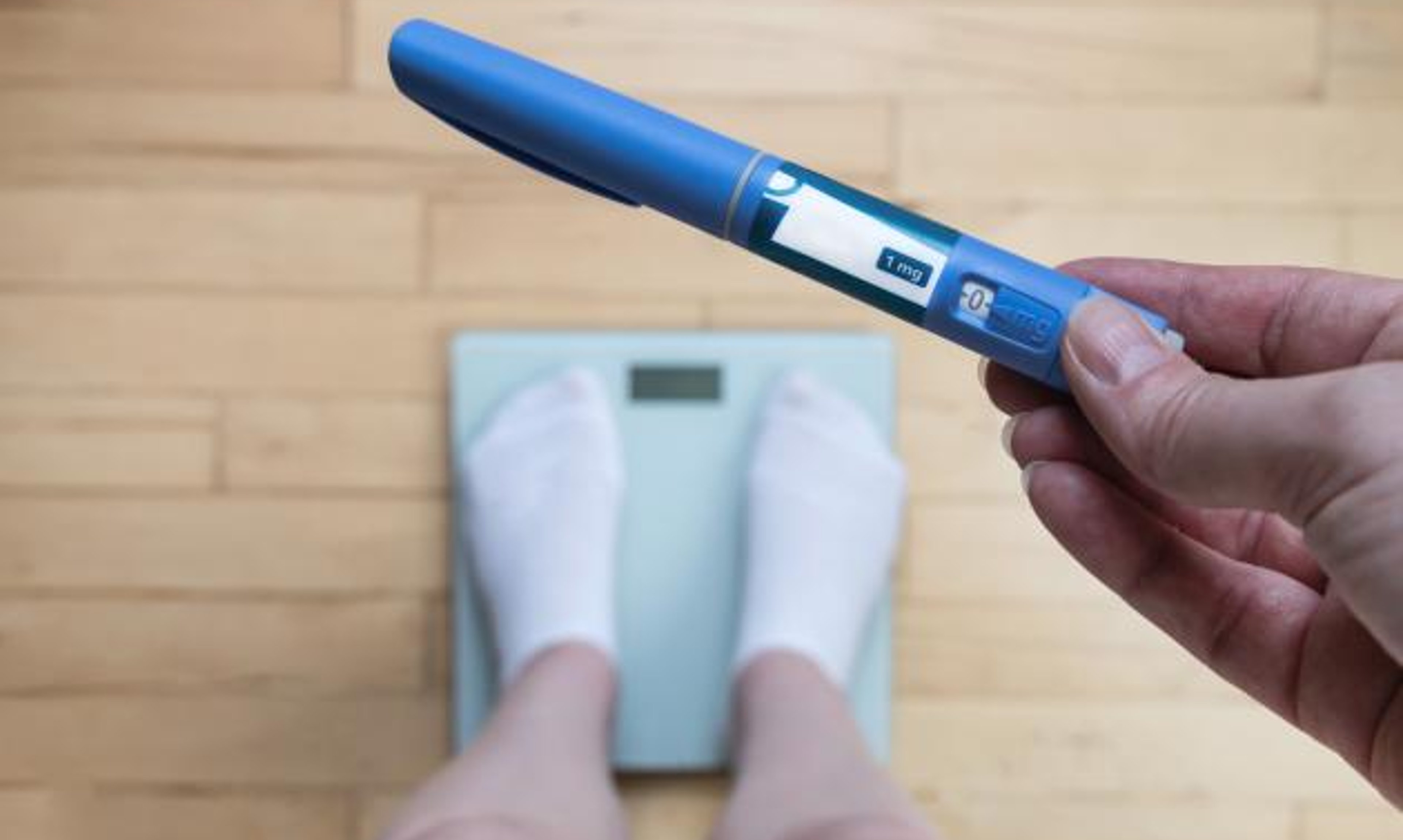 person standing on scale holding injection pen
