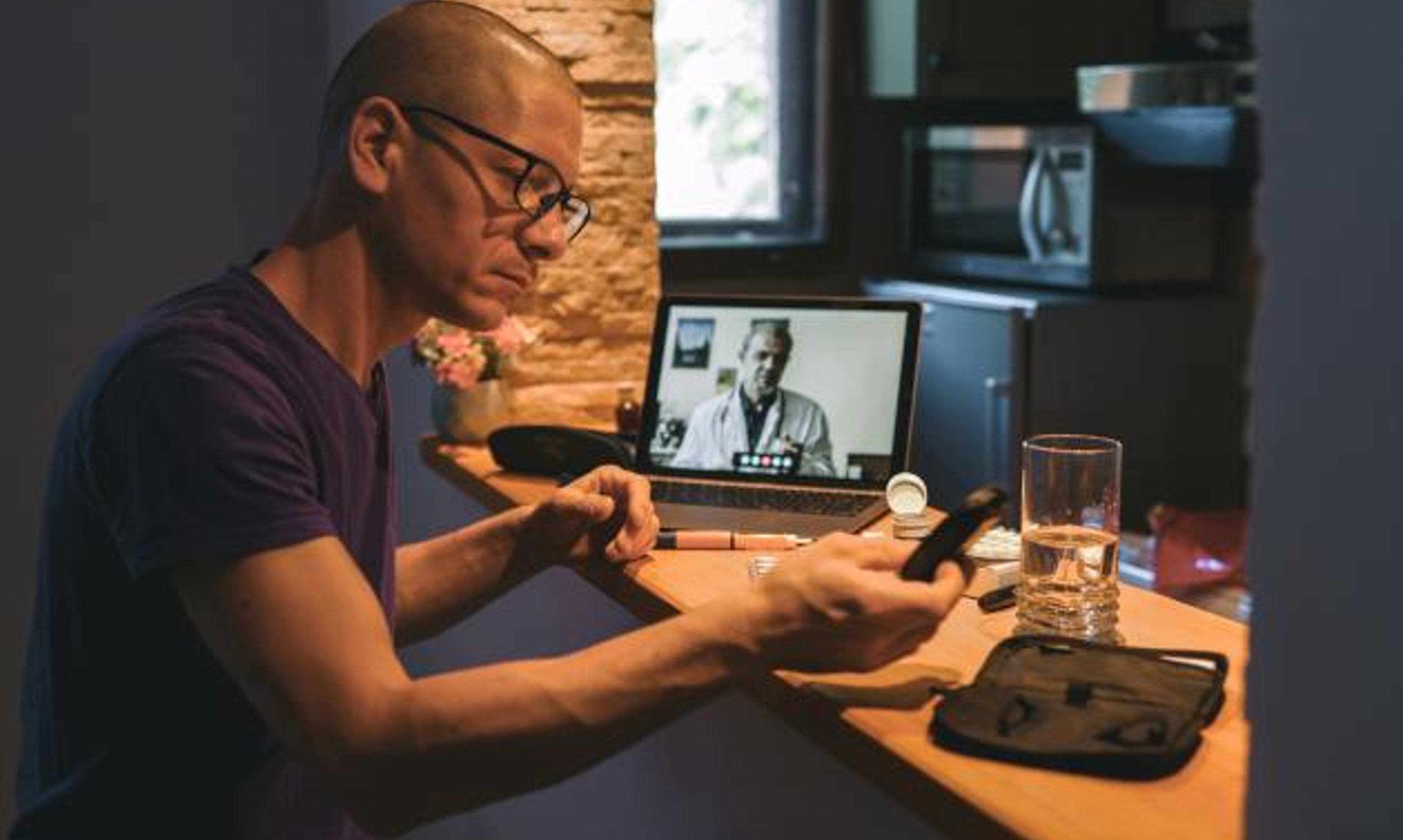 A man looks at a glucometer in his home during a telehealth visit.