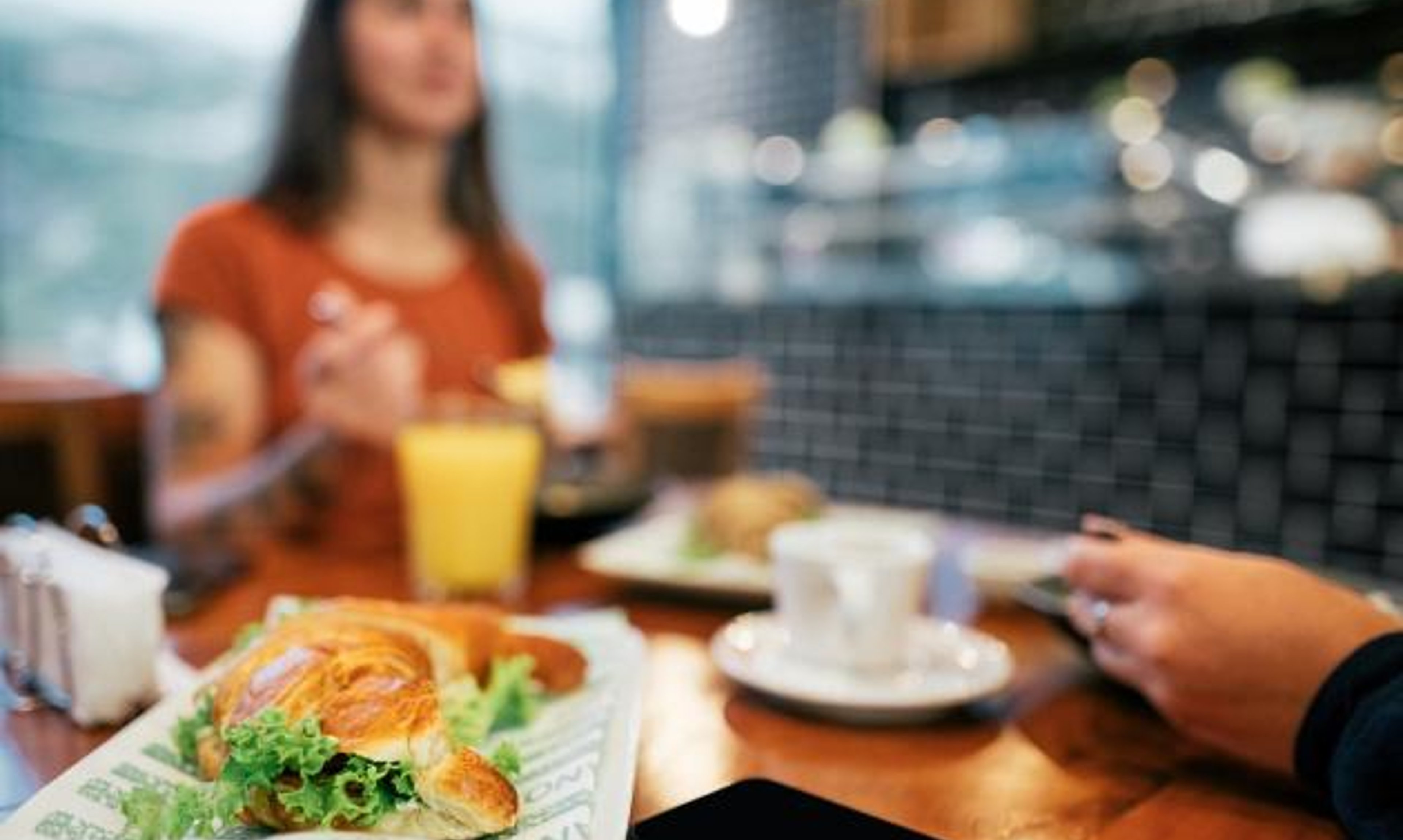 A smartphone sits on a table at a restaurant during a meal.