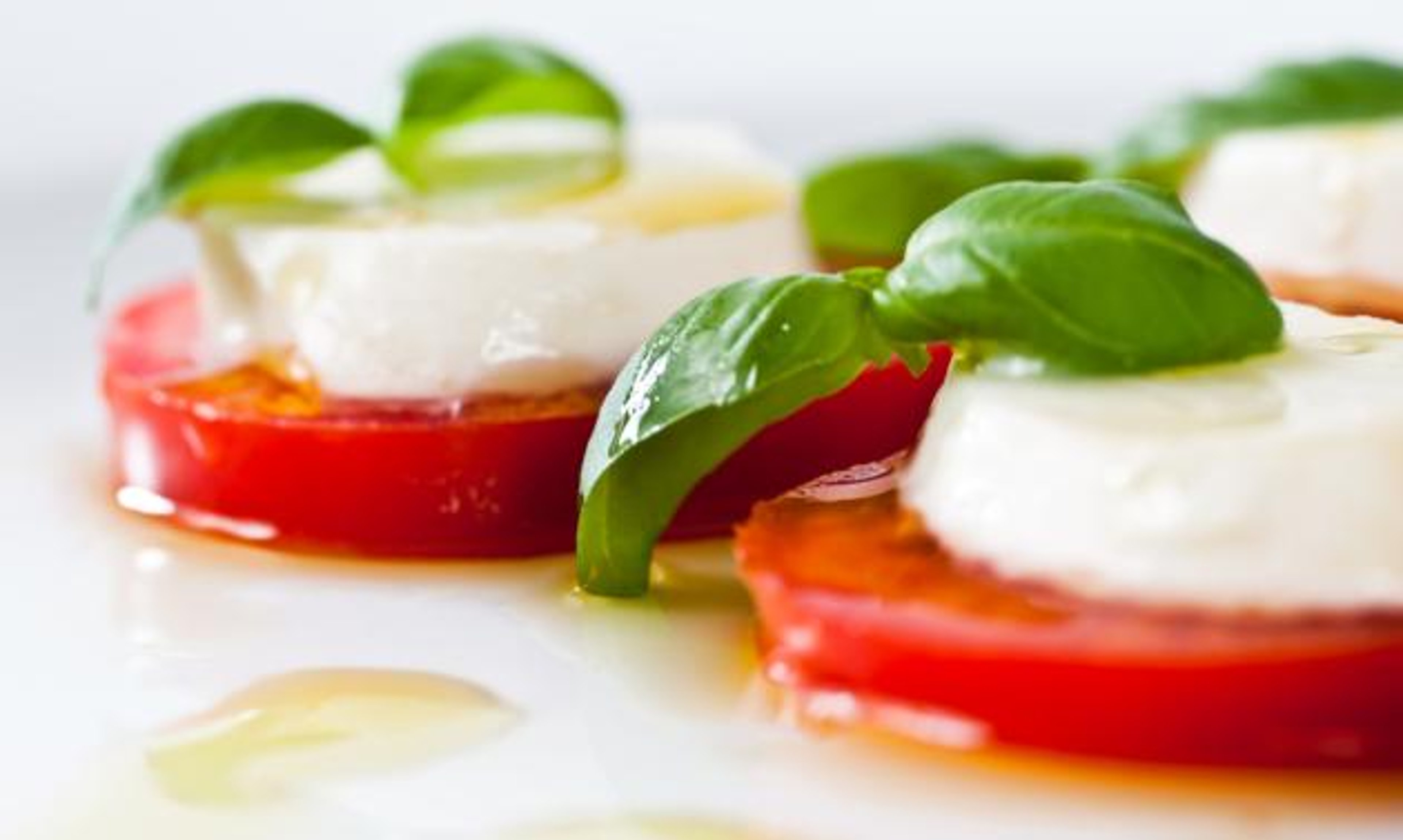 Stacks of mozzarella and tomato slices with olive oil drizzle