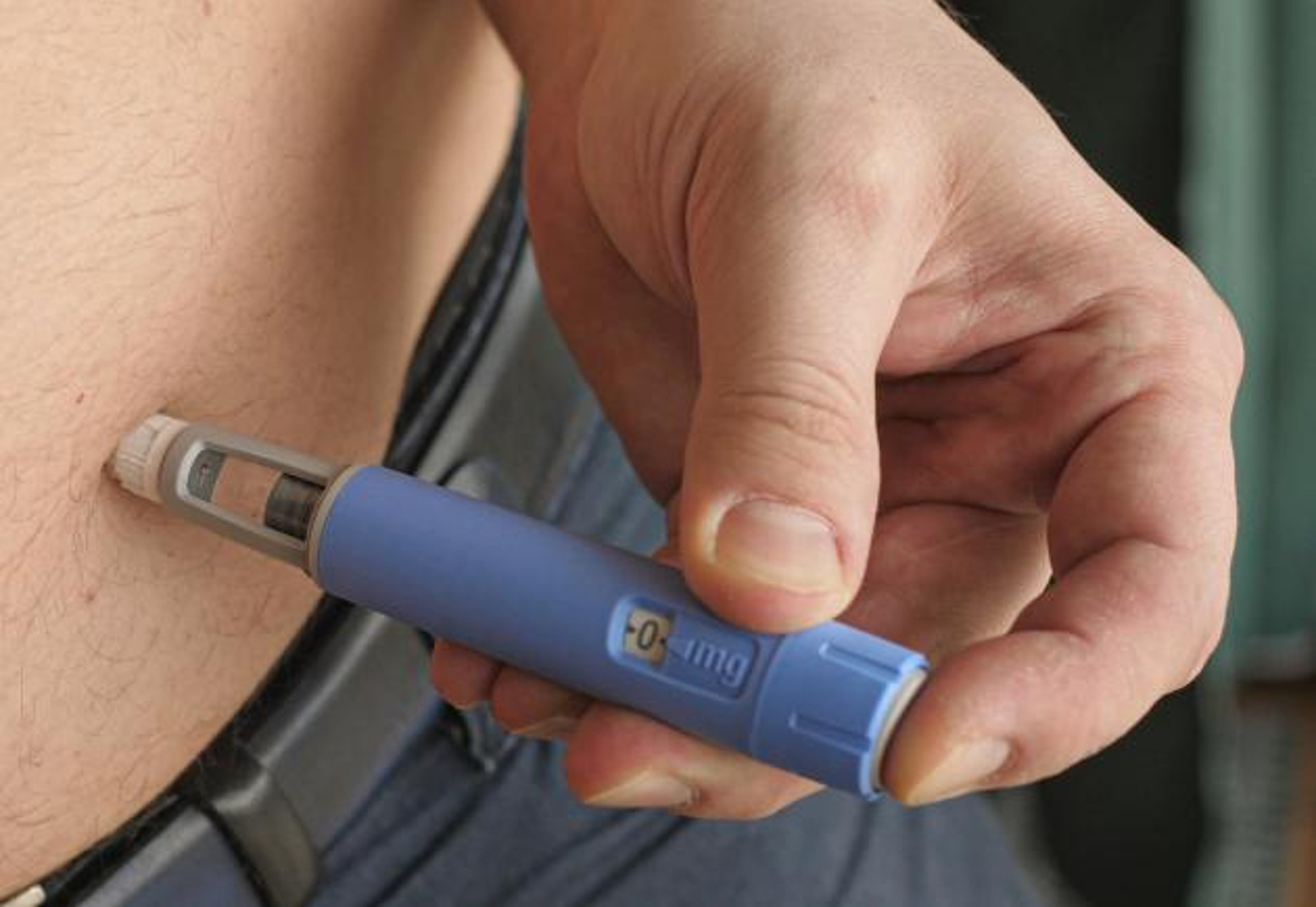 Man inserting Ozempic into stomach