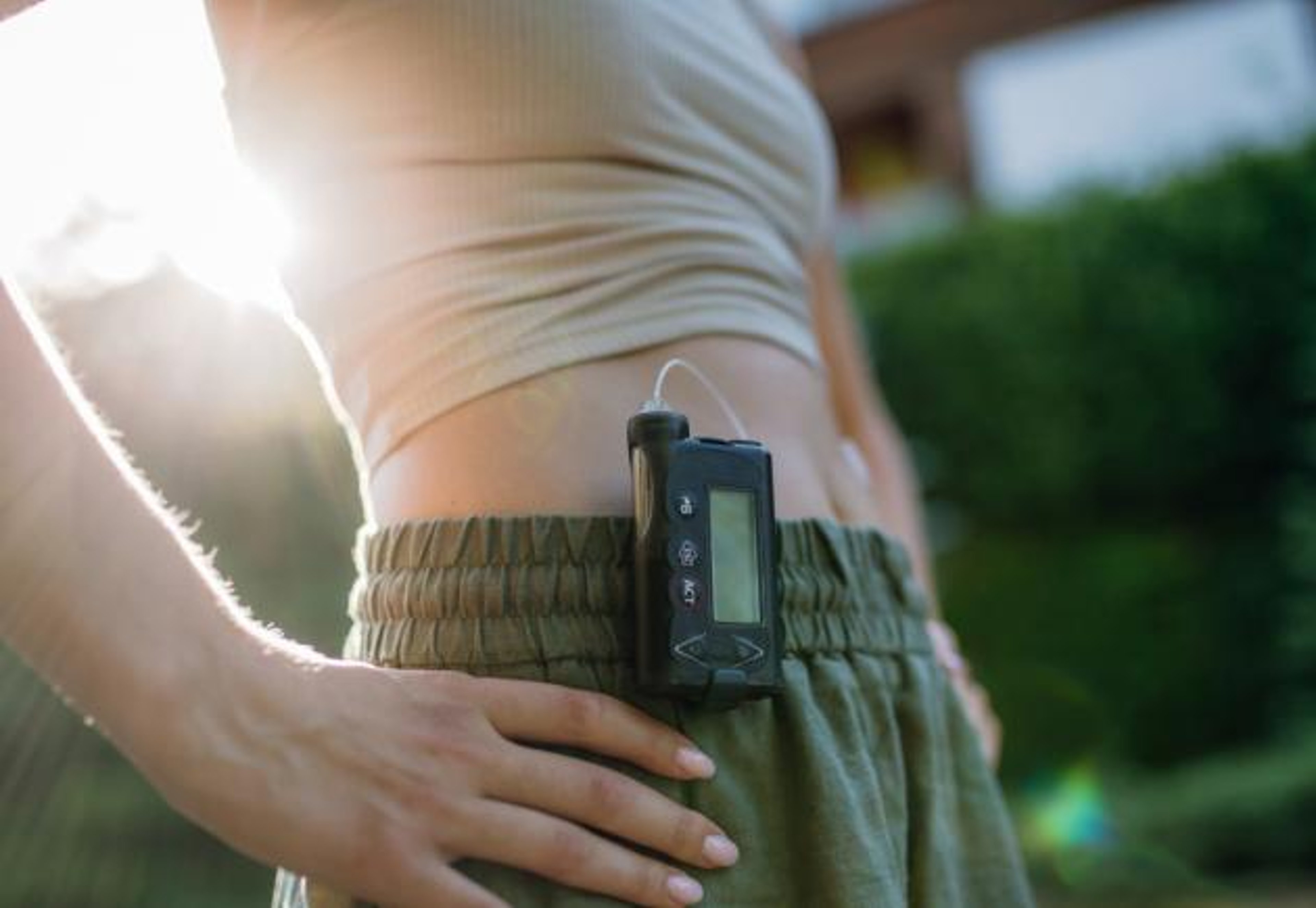 Woman wearing insulin pump with sun rising behind her.