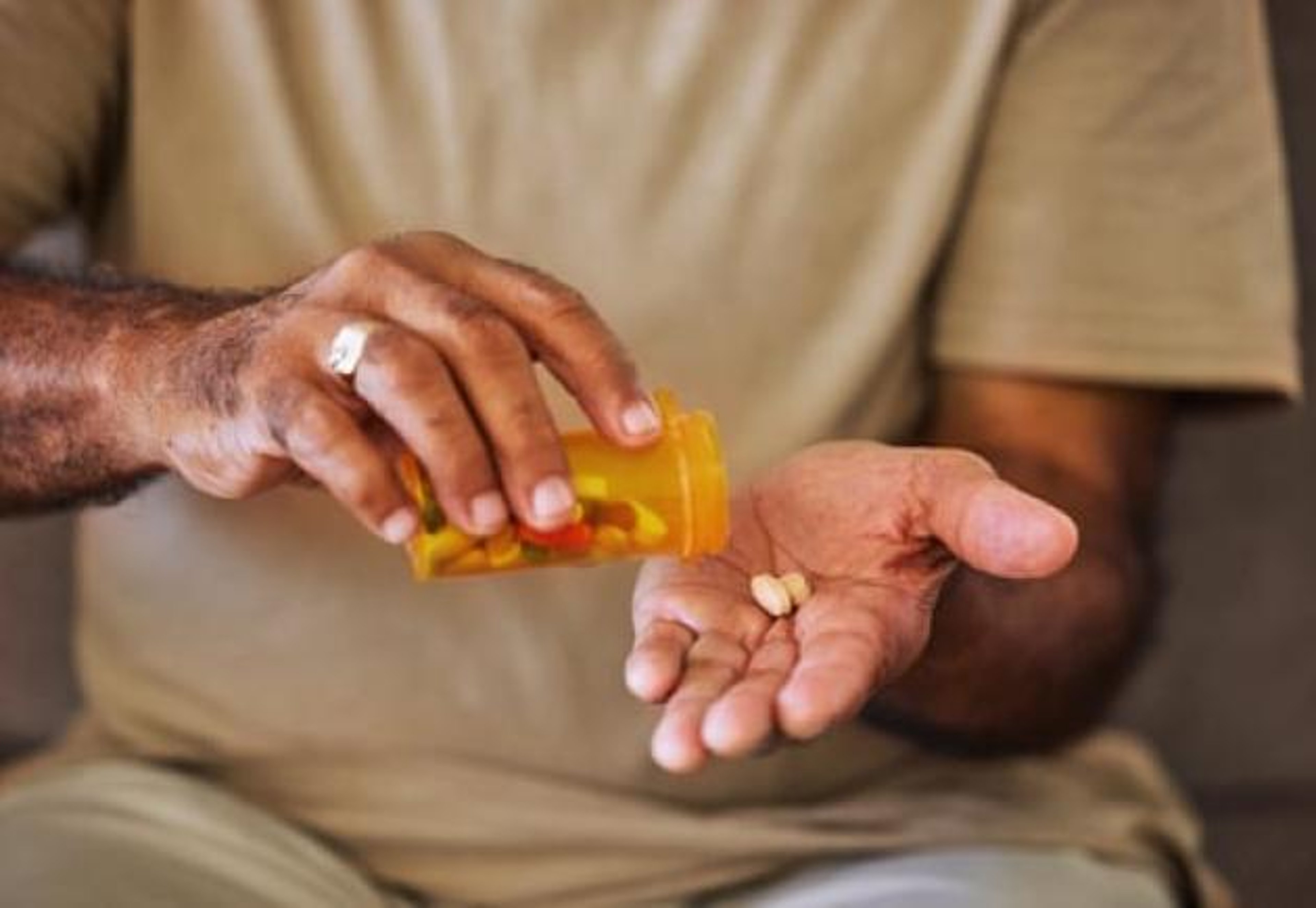 Man pours pills into his hand.