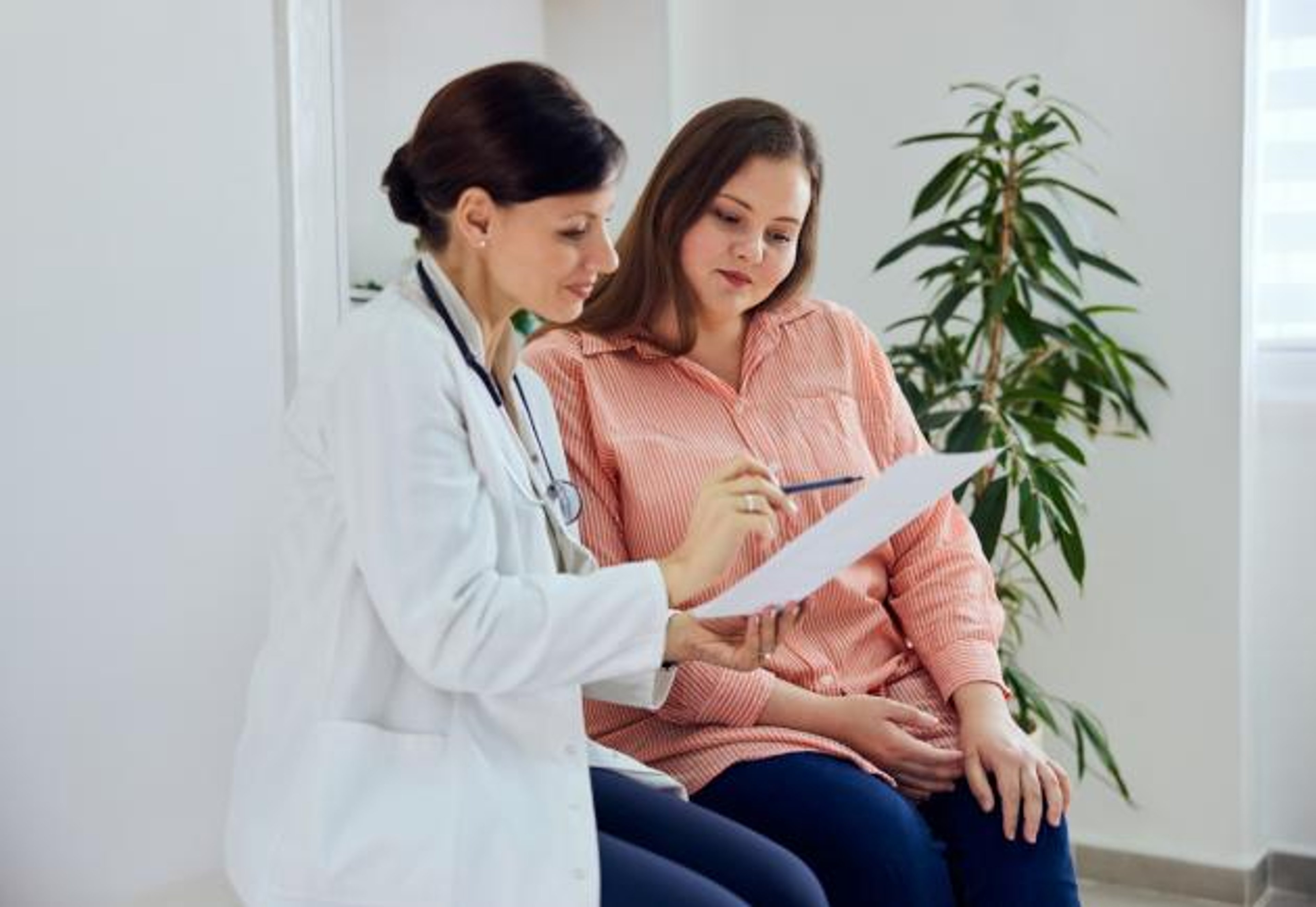 Woman reviewing paperwork with doctor and smiling