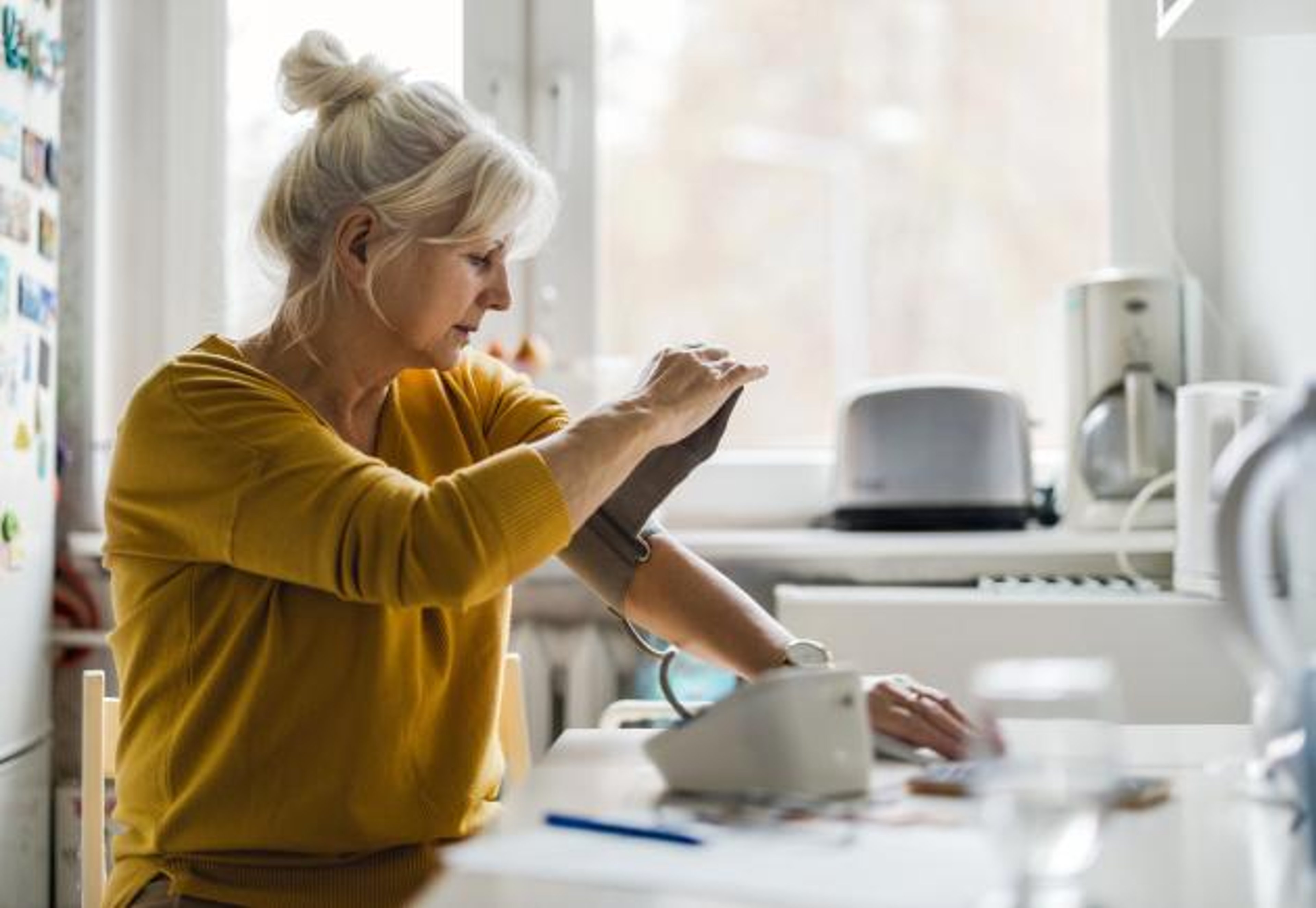 A woman checks her blood pressure at home.