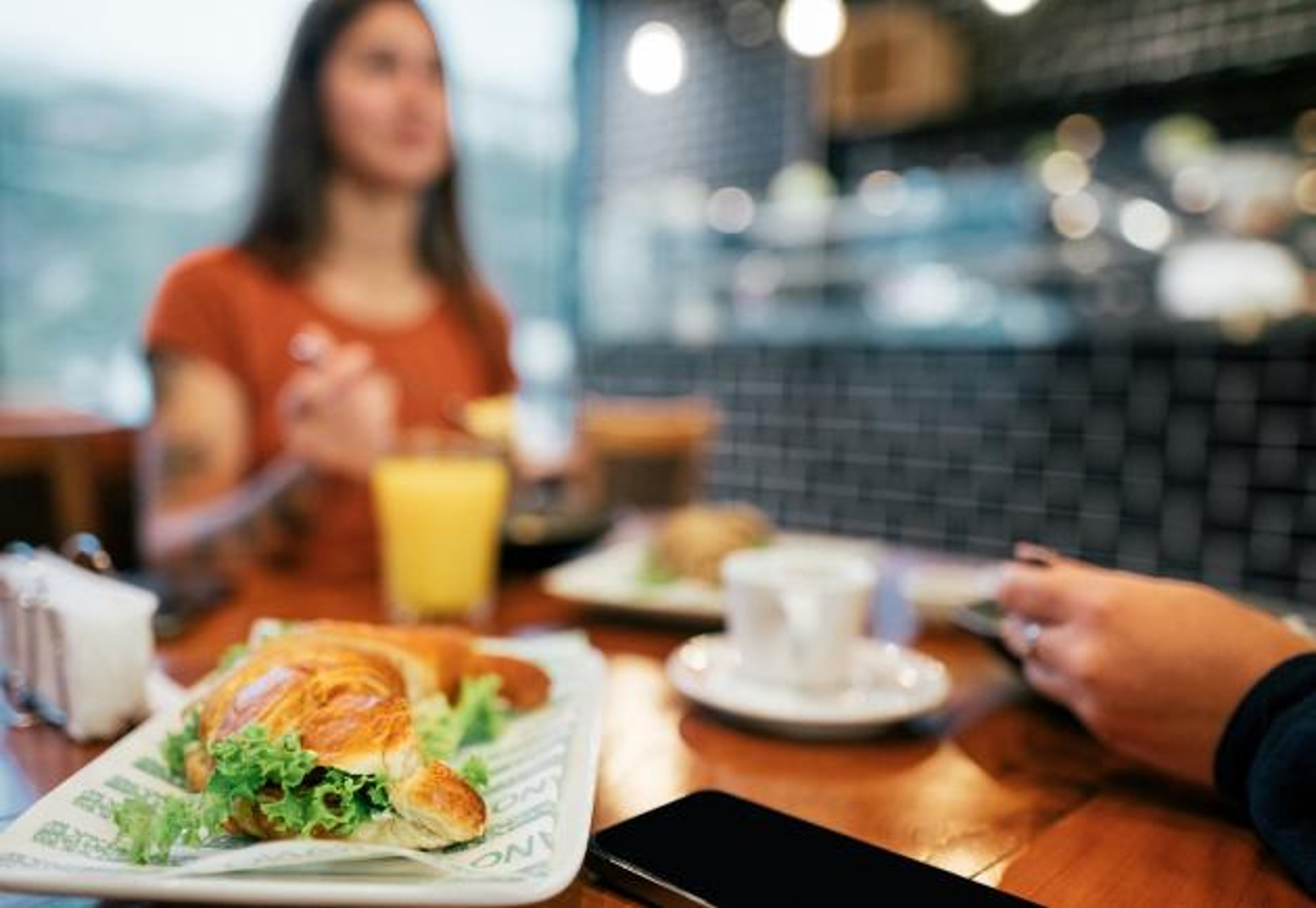 A smartphone sits on a table at a restaurant during a meal.
