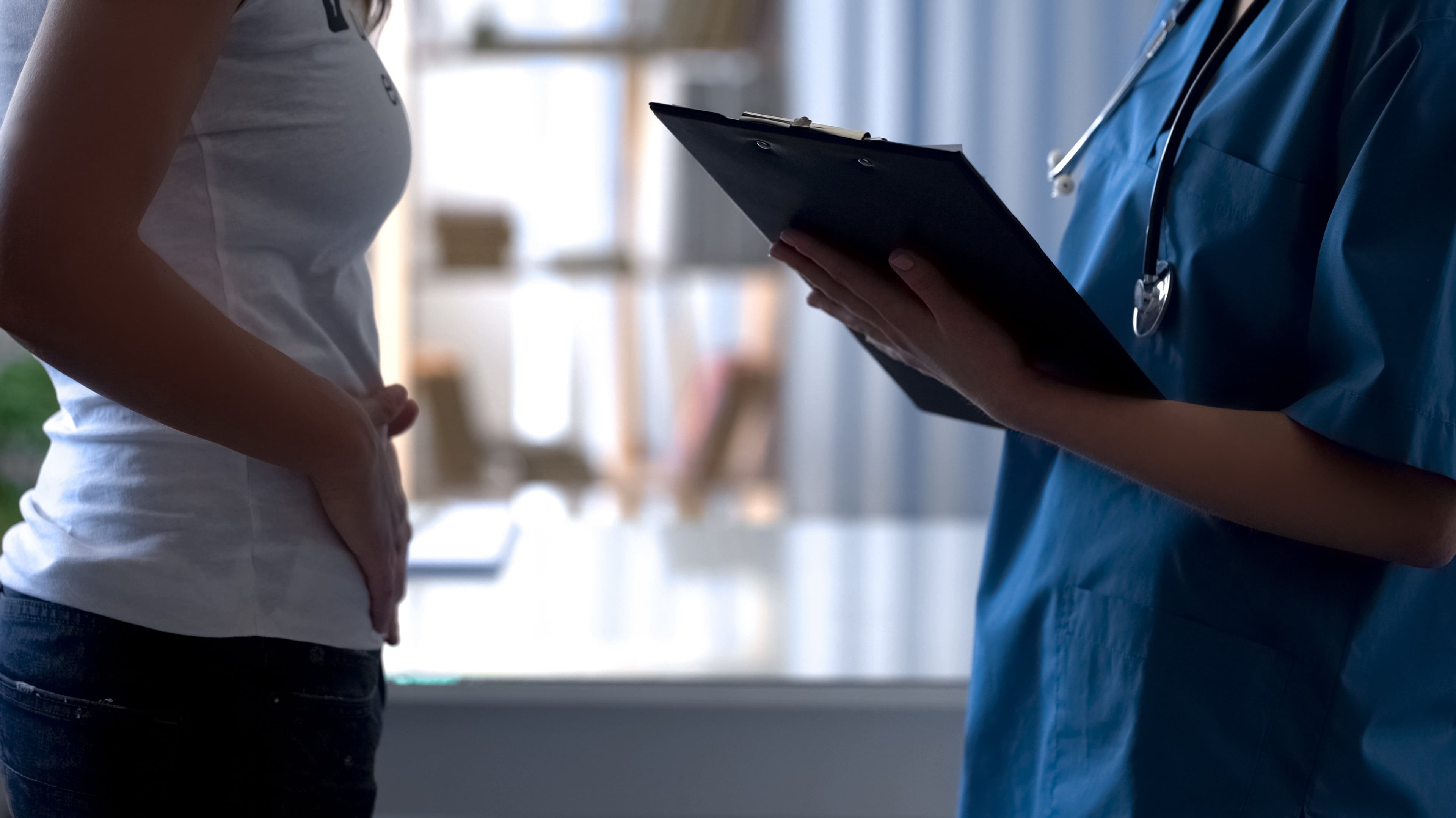 Woman talking to healthcare provider clutching abdomen