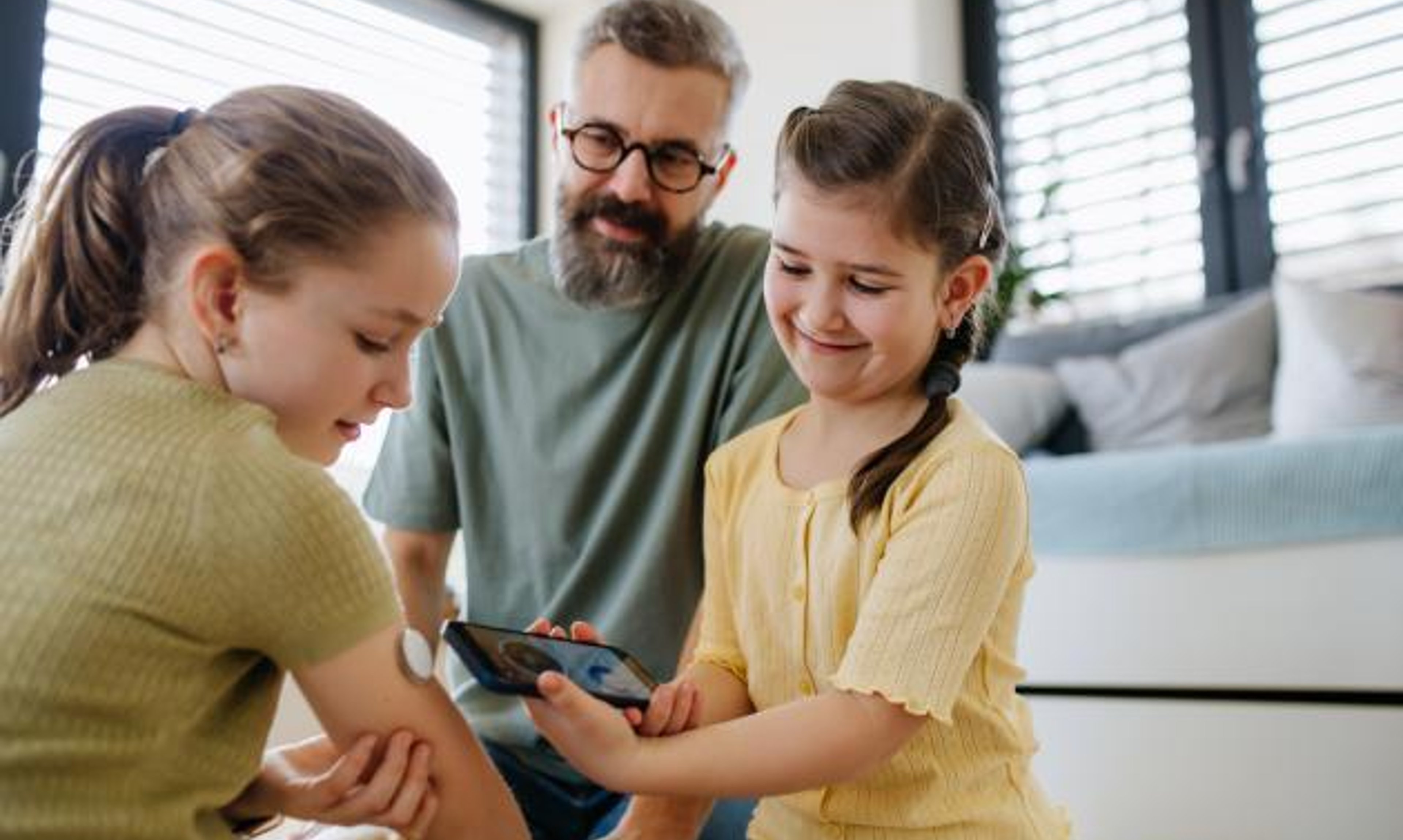 A girl with a CGM and her sister and father
