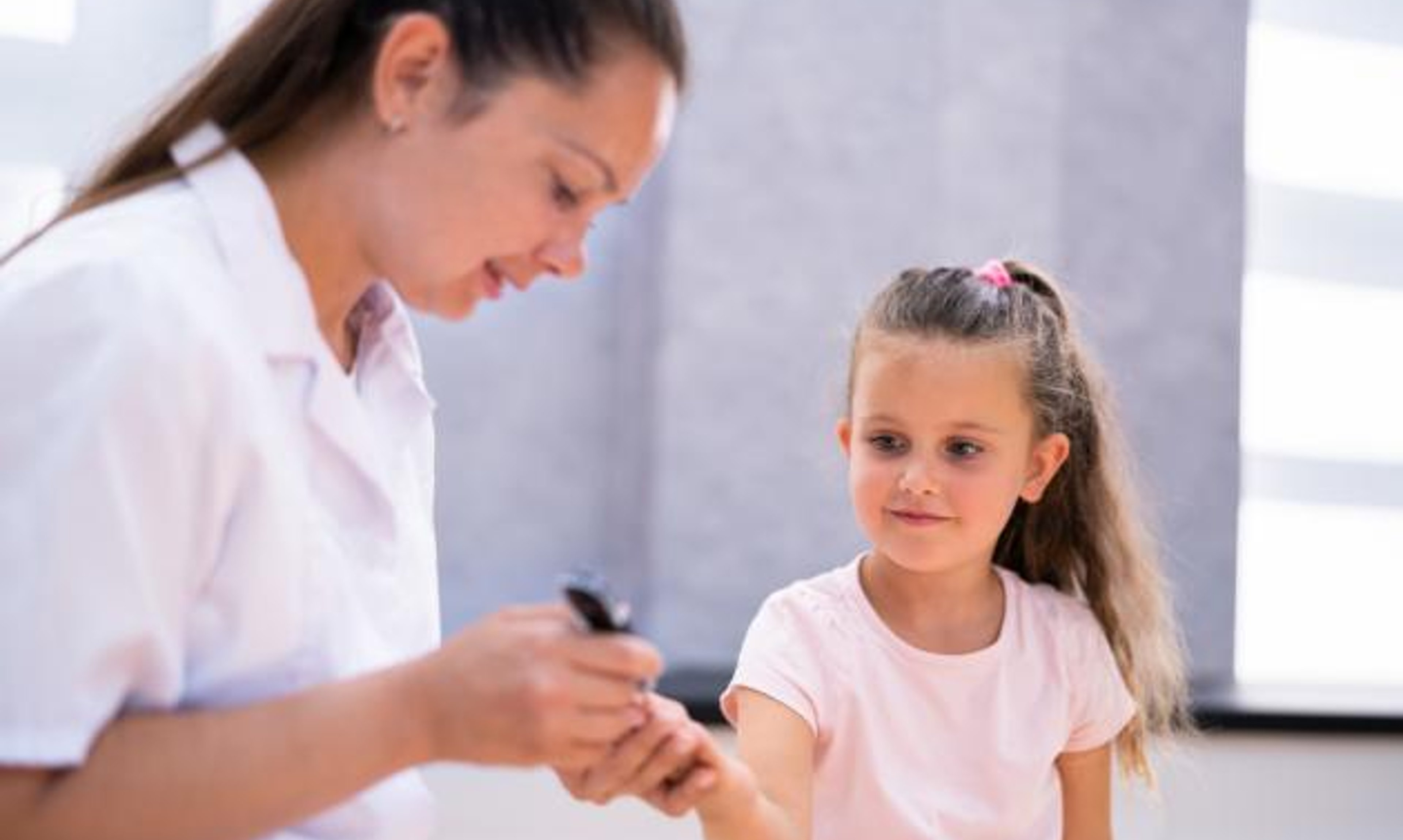 A woman uses a lancet for a finger prick blood test for a child.