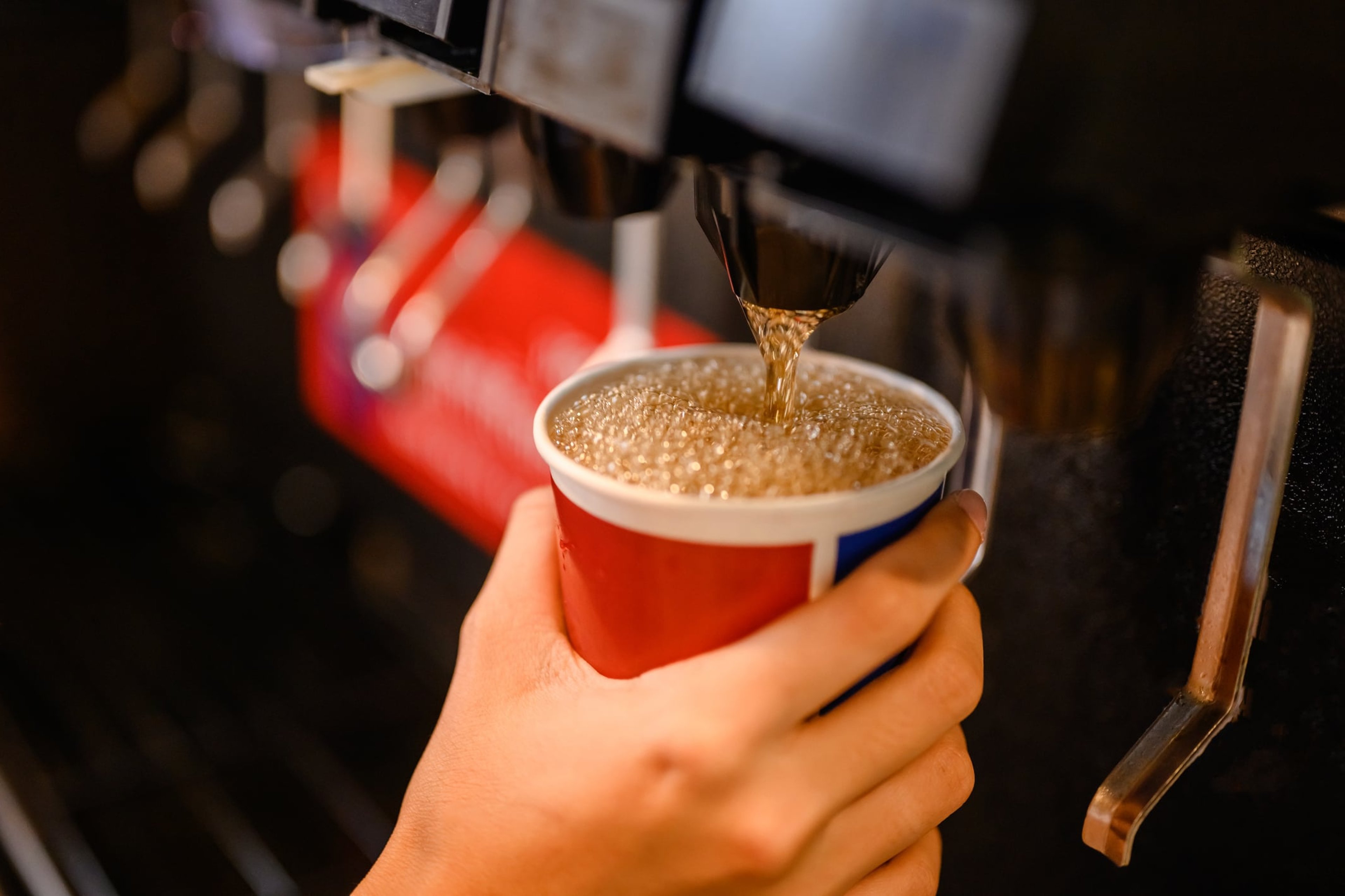 Close-up of dispensing cola at a soda fountain station