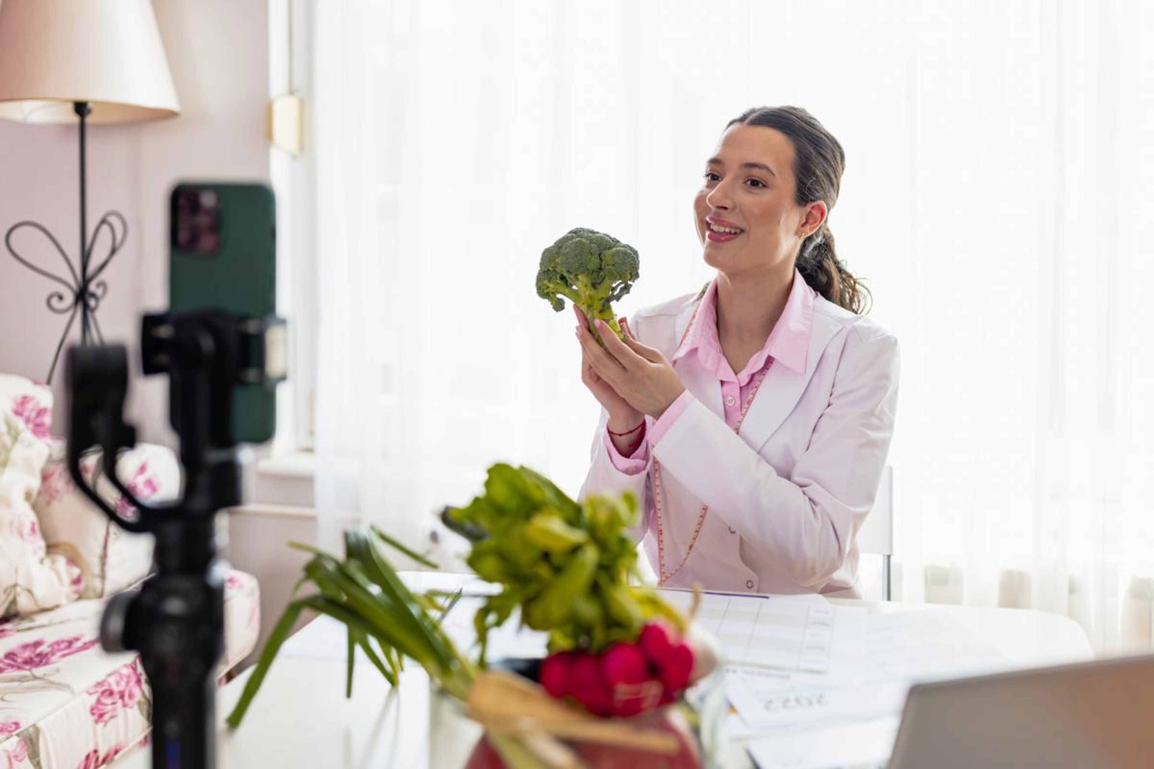 A registered dietitian holds a piece of broccoli up
