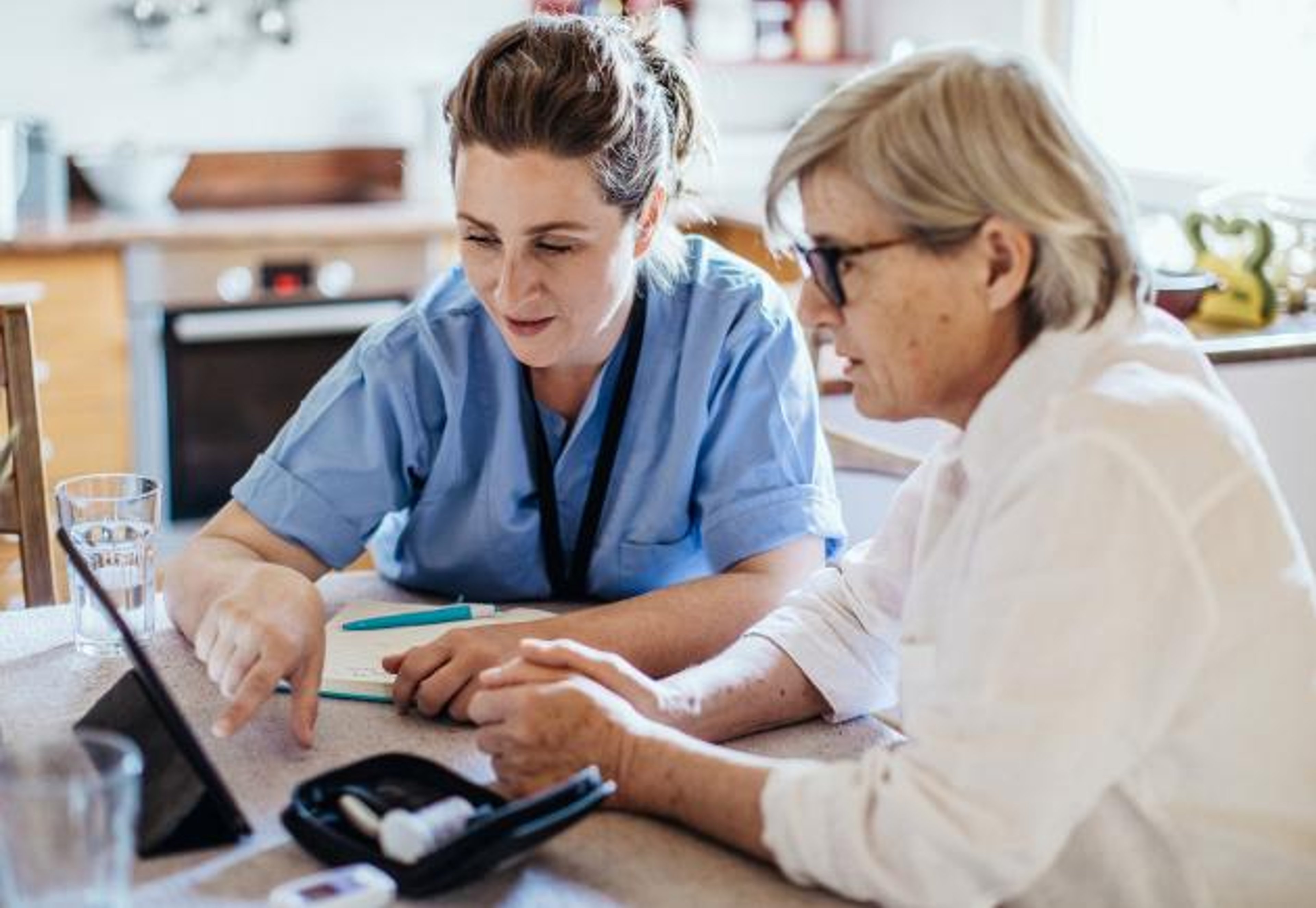 A healthcare worker teaches a patient using a tablet