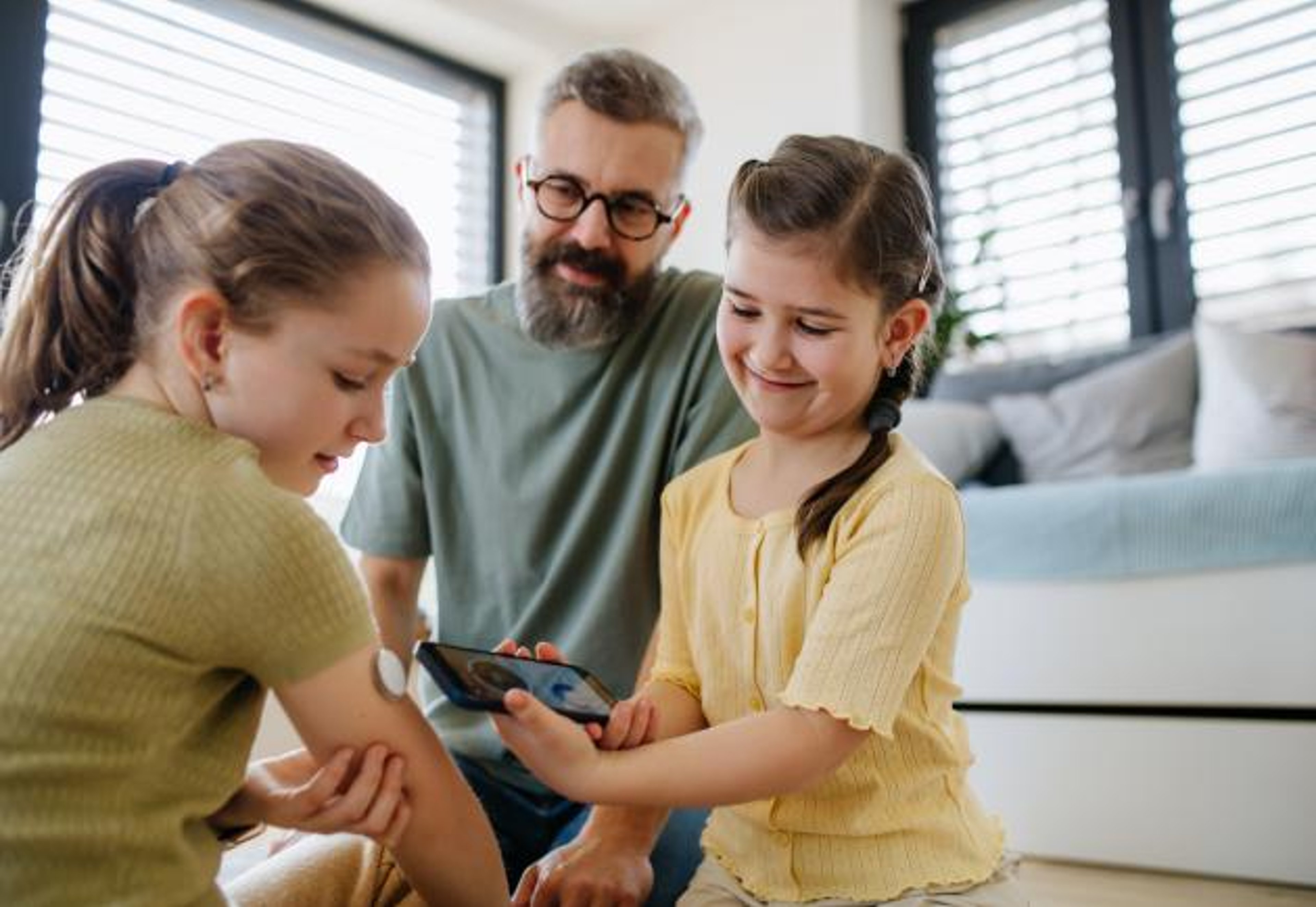 A girl with a CGM and her sister and father