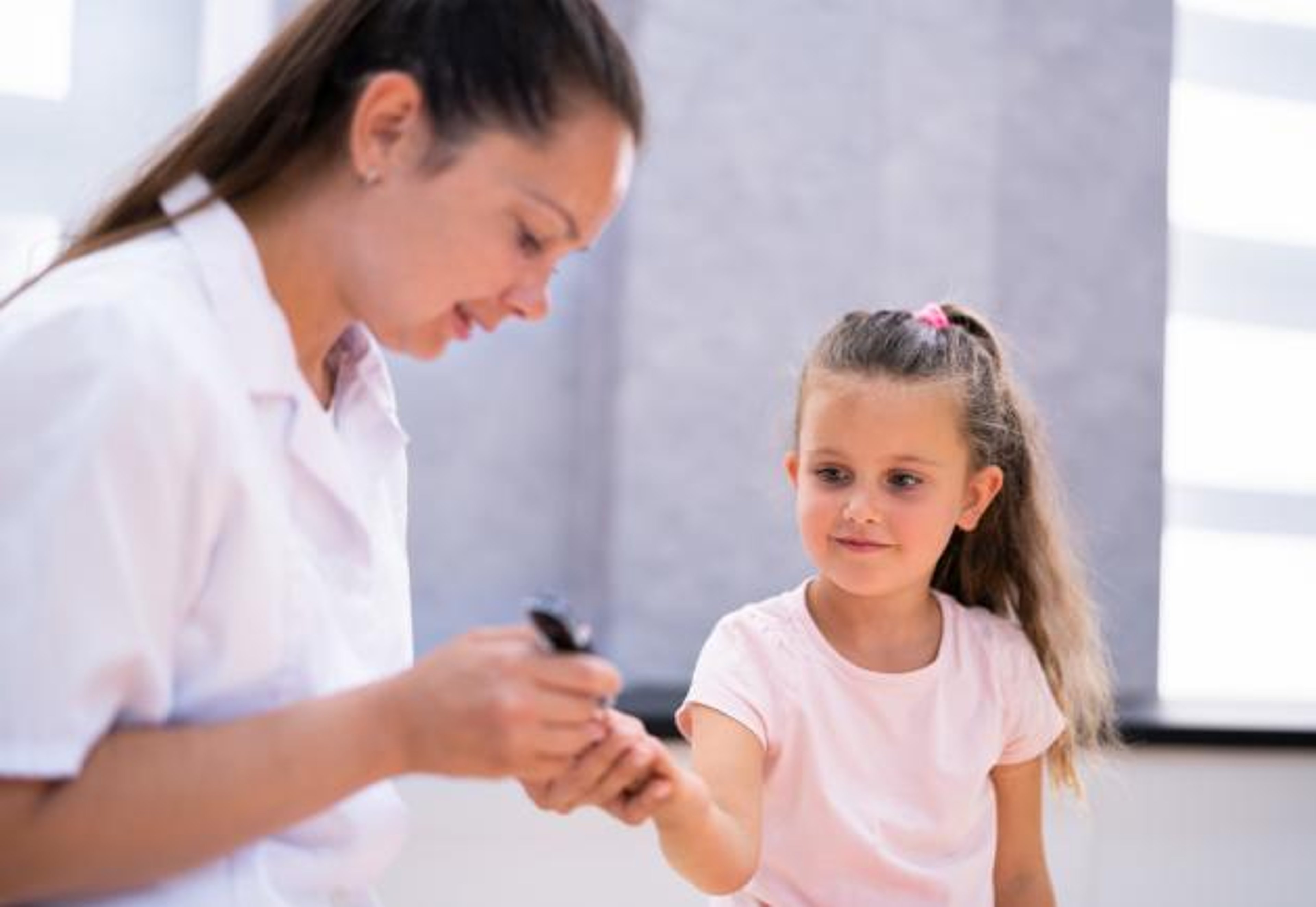A woman uses a lancet for a finger prick blood test for a child.