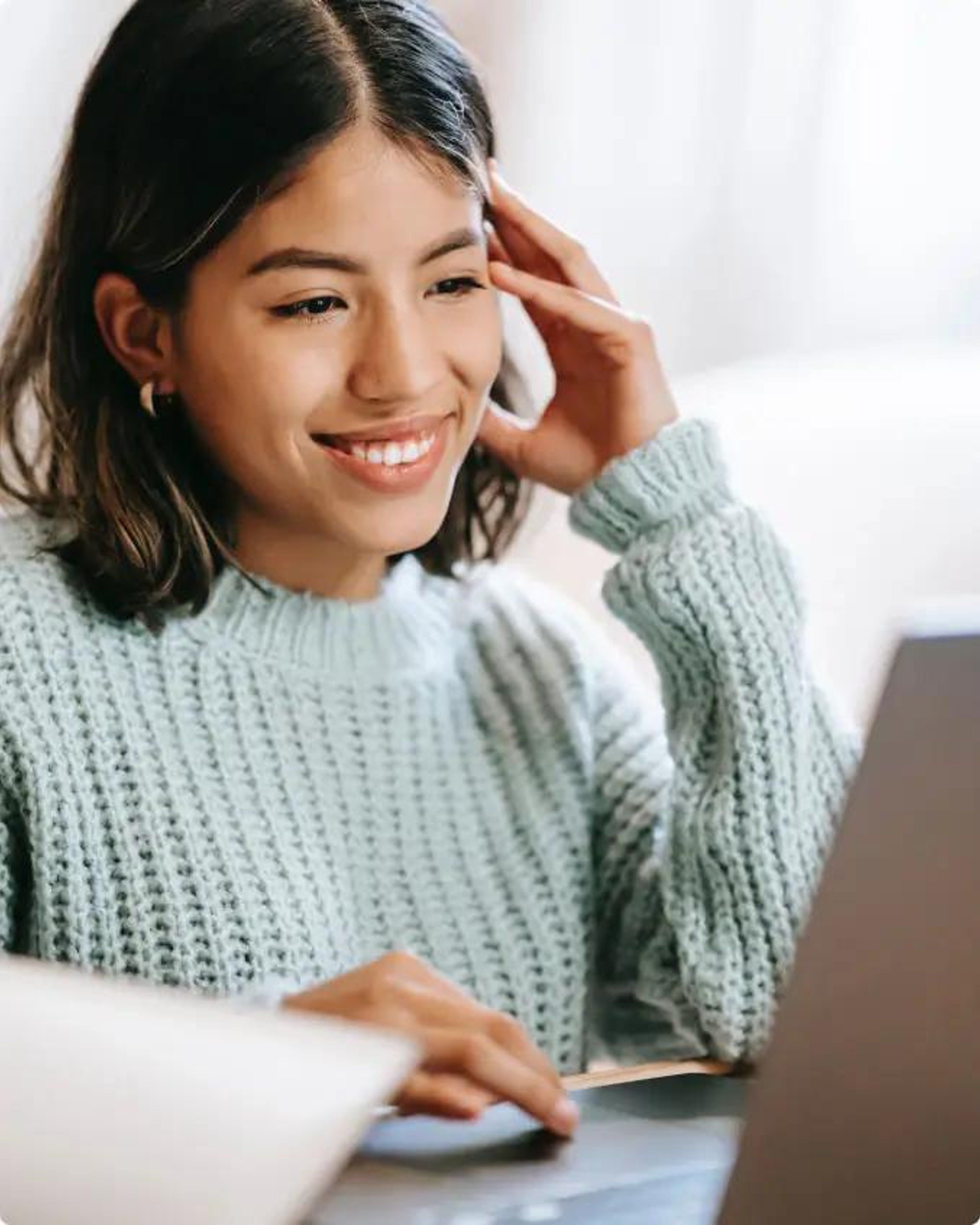 A smiling woman working with a laptop behind a desk