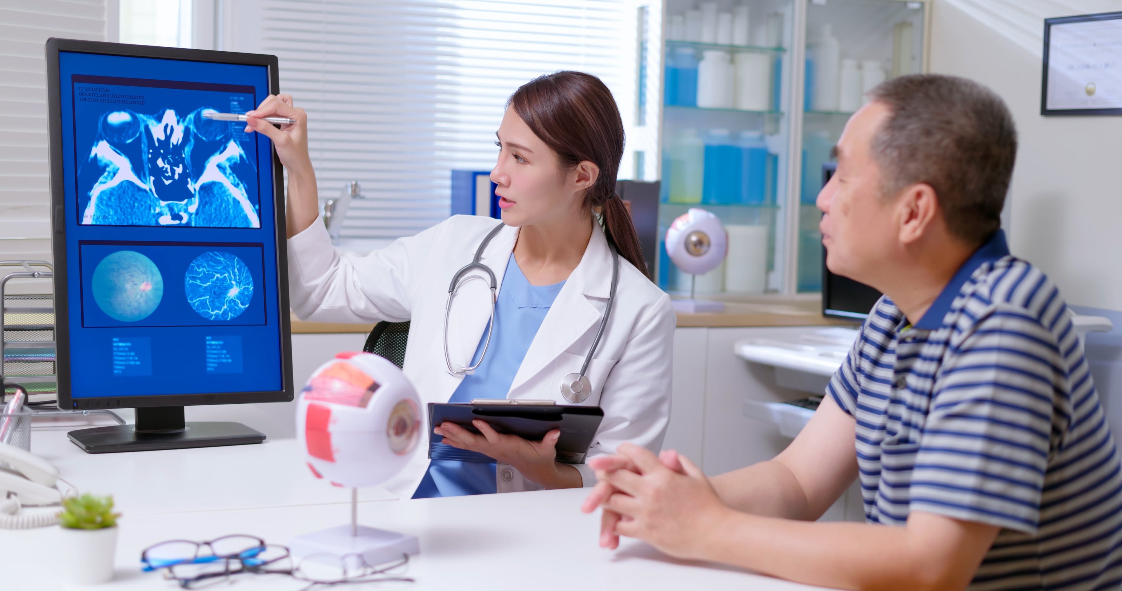 Woman reviewing eye model on screen with a seated man