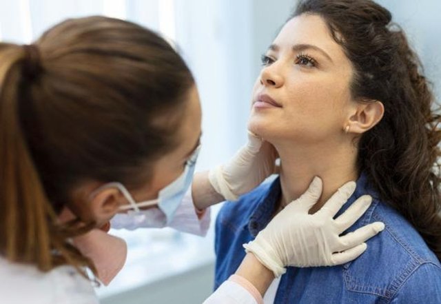 A healthcare provider examines a patient's thyroid 