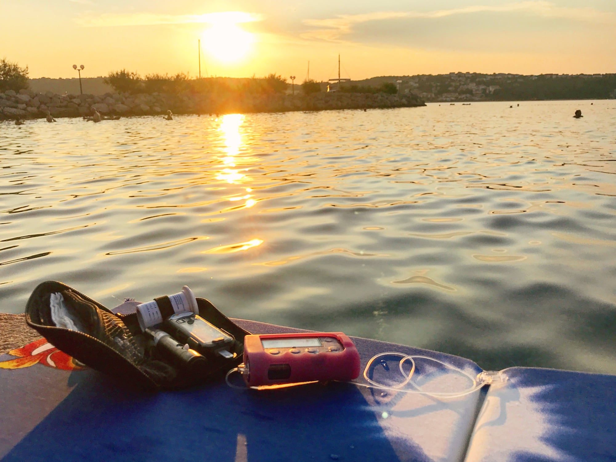 An insulin pump on a float on a lake with the sun setting.