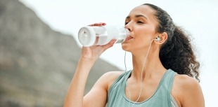 A woman stays hydrated during physical activity by drinking from a water bottle